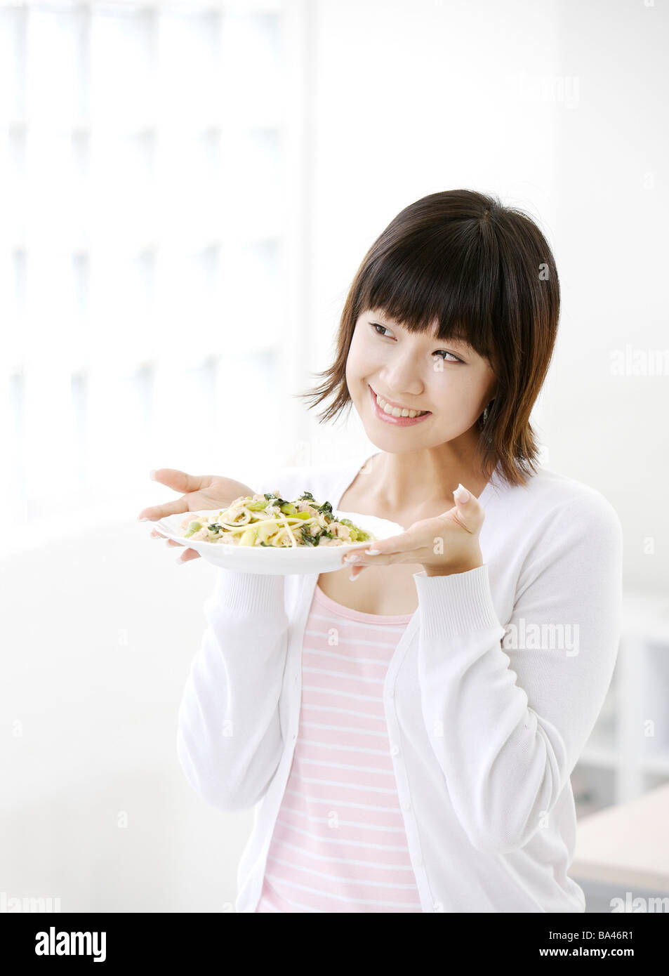 Junge Frau hält eine Gericht Lächeln, wegschauen Stockfoto