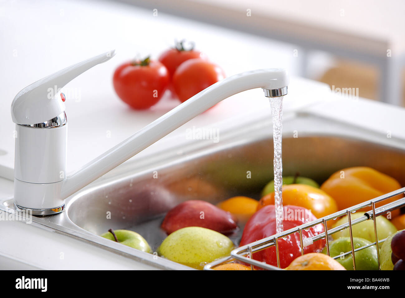 Wasser läuft aus einem Wasserhahn in der Spüle mit Früchten hautnah Stockfoto