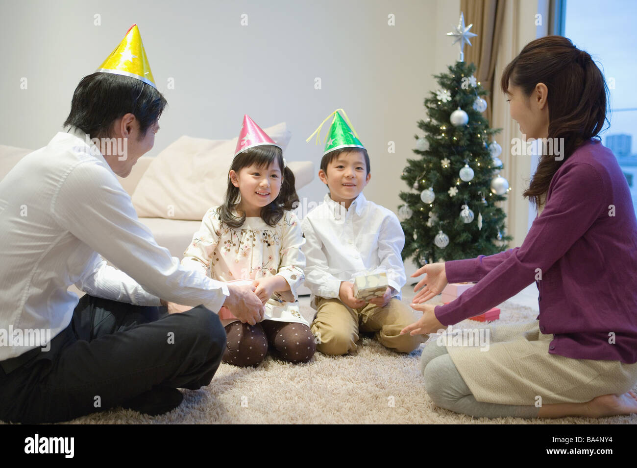 Familie tragen Partyhüte mit Geburtstagsgeschenk Stockfoto