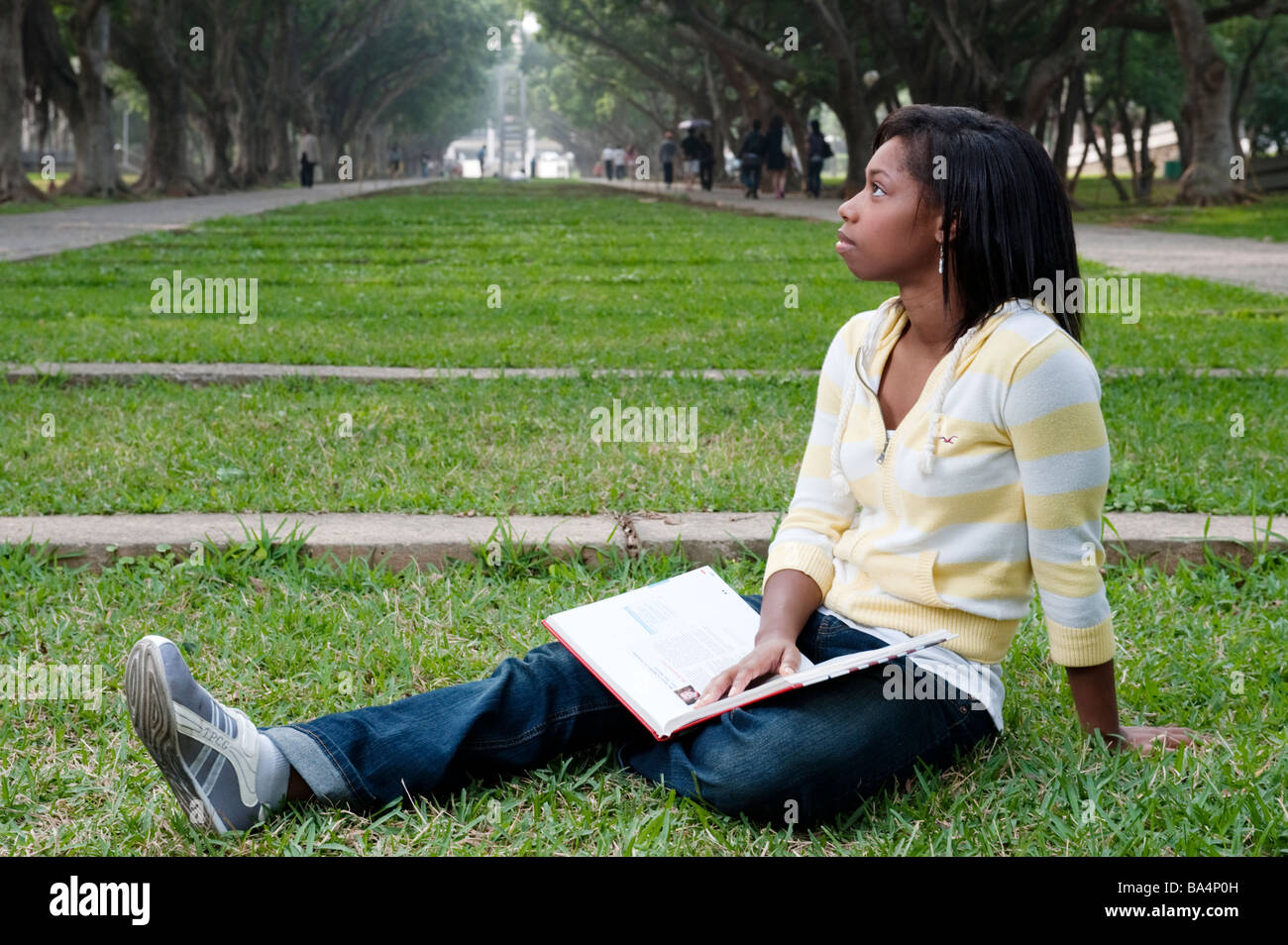 Junge Frau sitzt im Park Lesen eines Textes buchen studieren Stockfoto