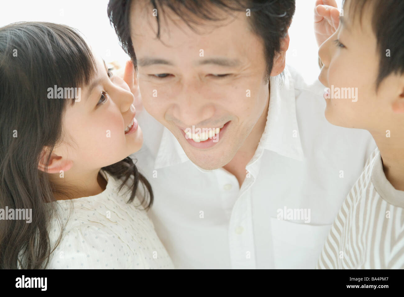 Sohn und Tochter in ihren Vater Ohren flüstern Stockfoto