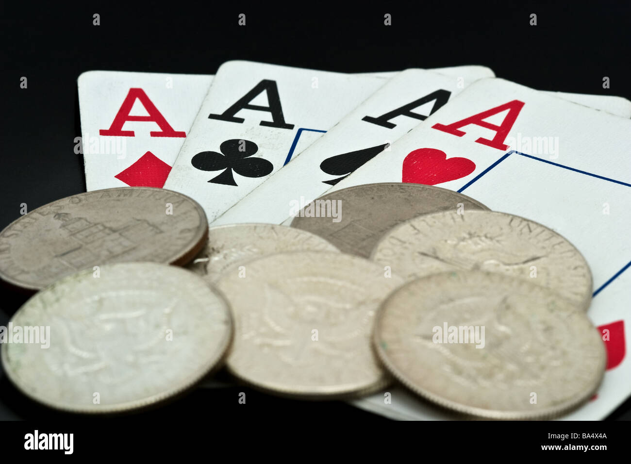 Vier Asse unter einem Haufen von American halb-Dollar-Münzen Stockfoto