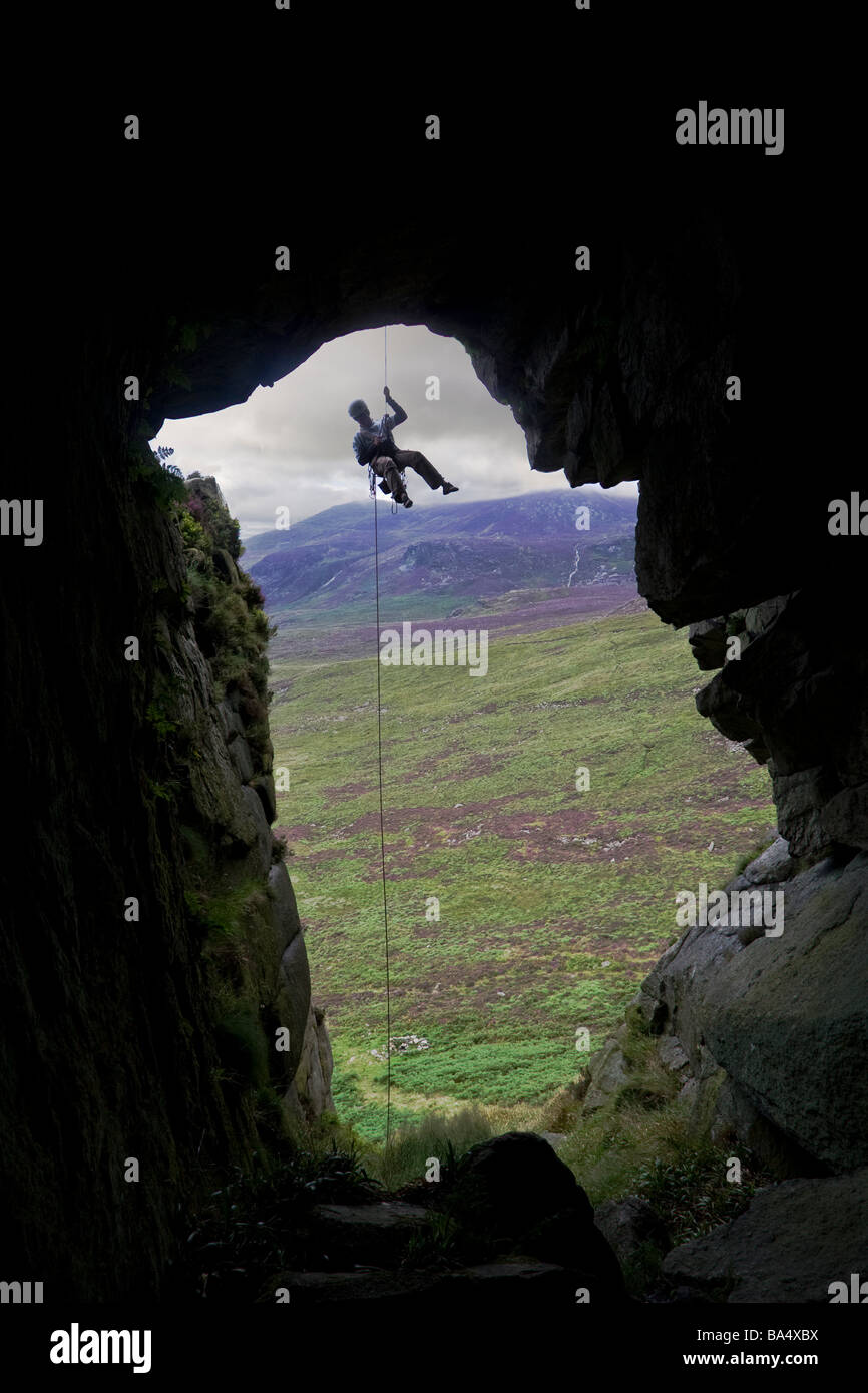 Abseling über dem Eingang einer Berghöhle auf den britischen Inseln Stockfoto