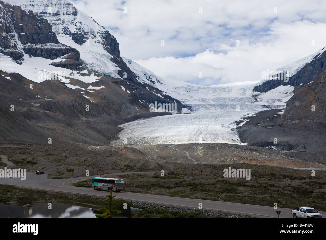 Straße mit schneebedeckten Bergen gegen bewölktem Himmel Stockfoto