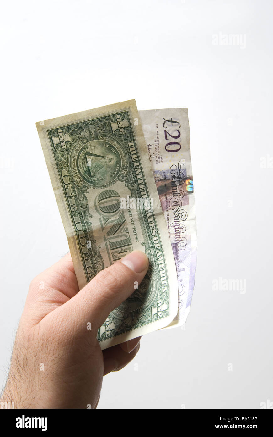 Hand, die eine amerikanische eine Dollarnote und zwanzig Pfund britische Banknoten Stockfoto