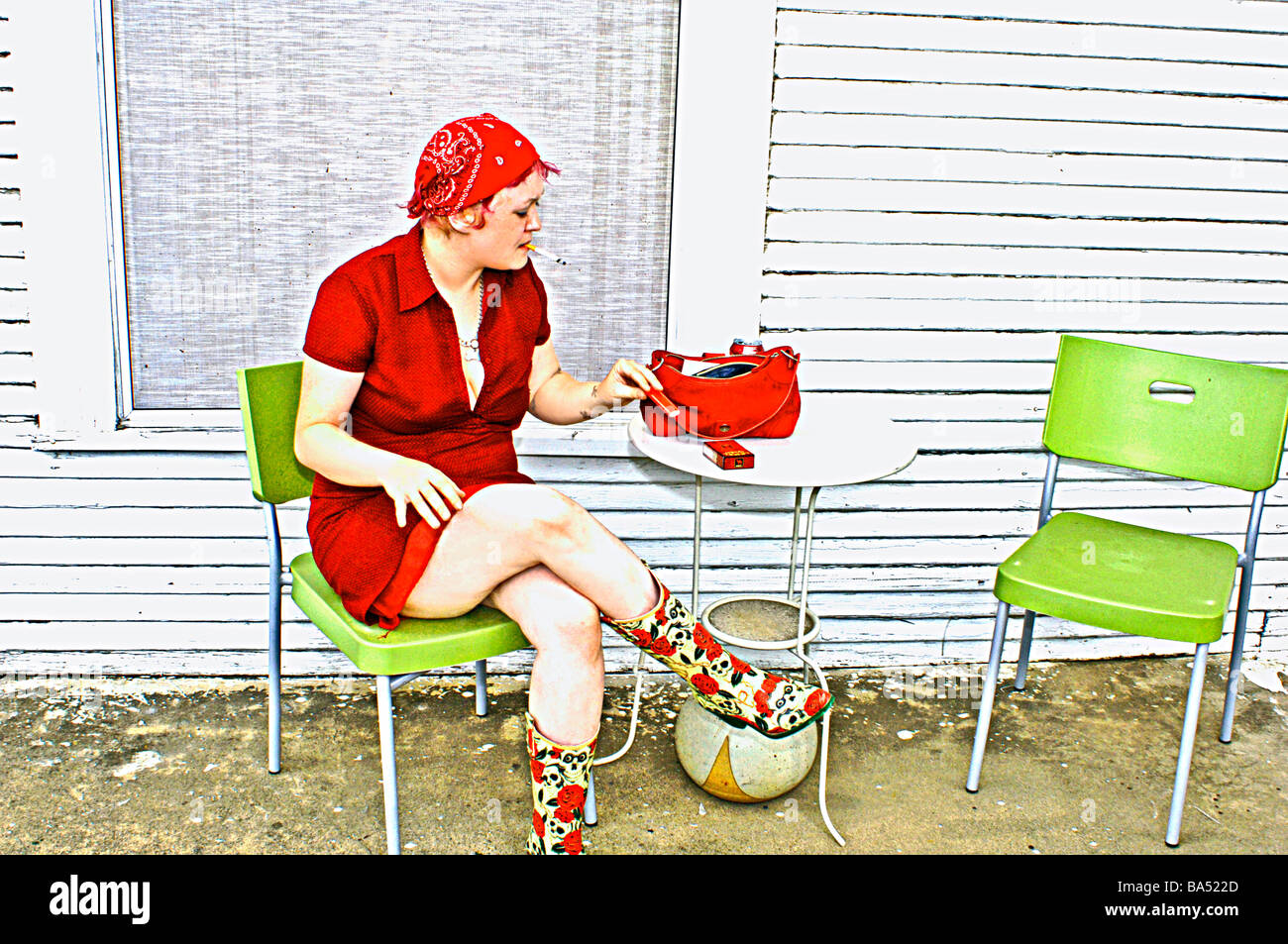Mittelklasse-Dame in leuchtend roten Kleid sitzt auf dem viktorianischen Baustil Veranda Rauchen Stockfoto