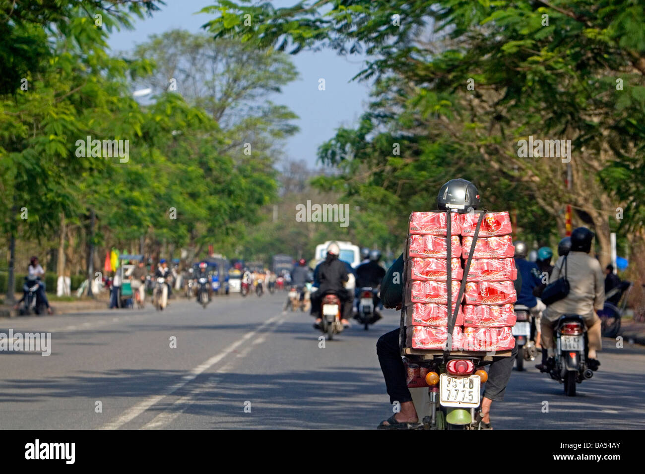 Vietnamesische Mann transportiert Fälle von Coca Cola auf der Rückseite von seinem Motorrad auf dem National Highway 1 in Hue, Vietnam Stockfoto