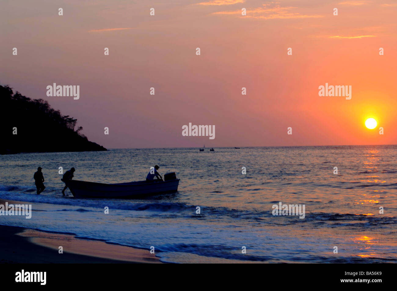 Fischer mit einem kleinen Boot auf einem tropischen Ozean in der Dämmerung Stockfoto