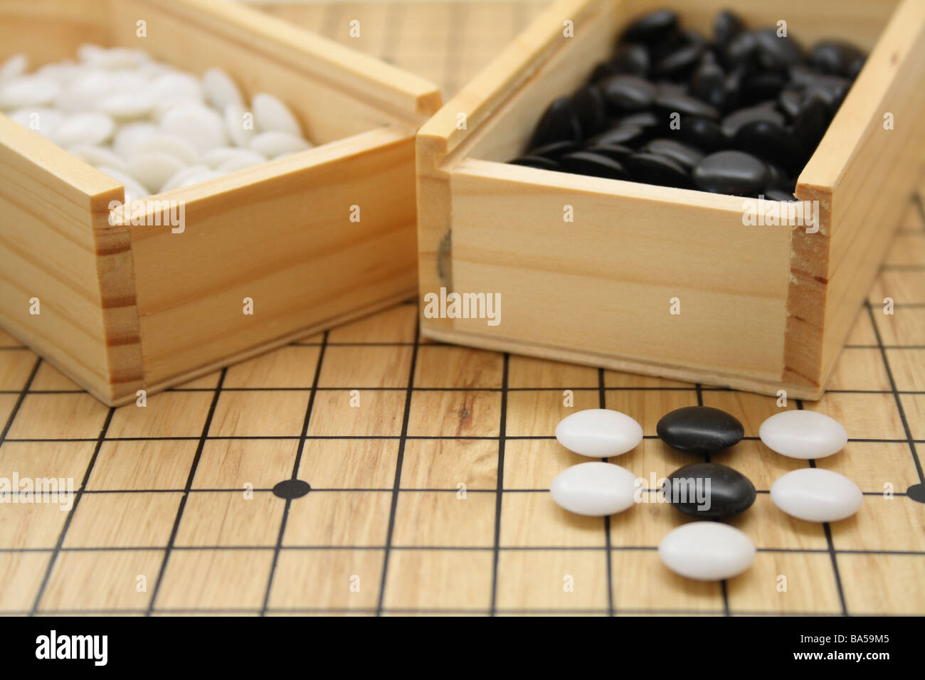 Go-Holzbrett mit schwarzen und weißen Stücke auf dem Brett und in ihrer hölzernen Behältern. Stockfoto