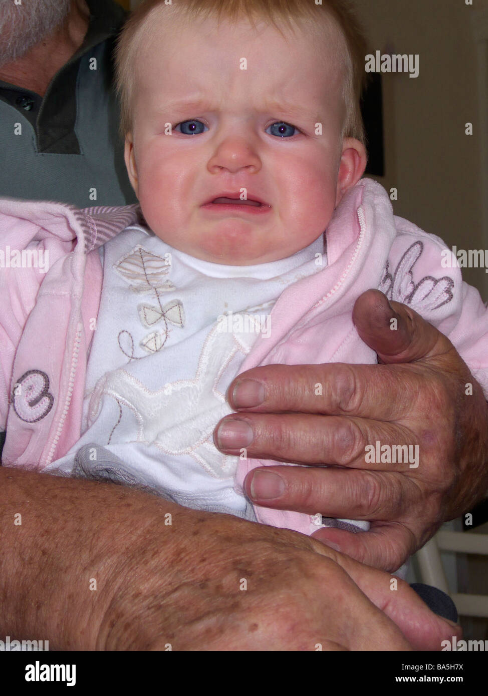 Ein kleines Mädchen beginnt zu weinen, als sie von einer Person gehalten wird ist sie nicht kennen. Stockfoto
