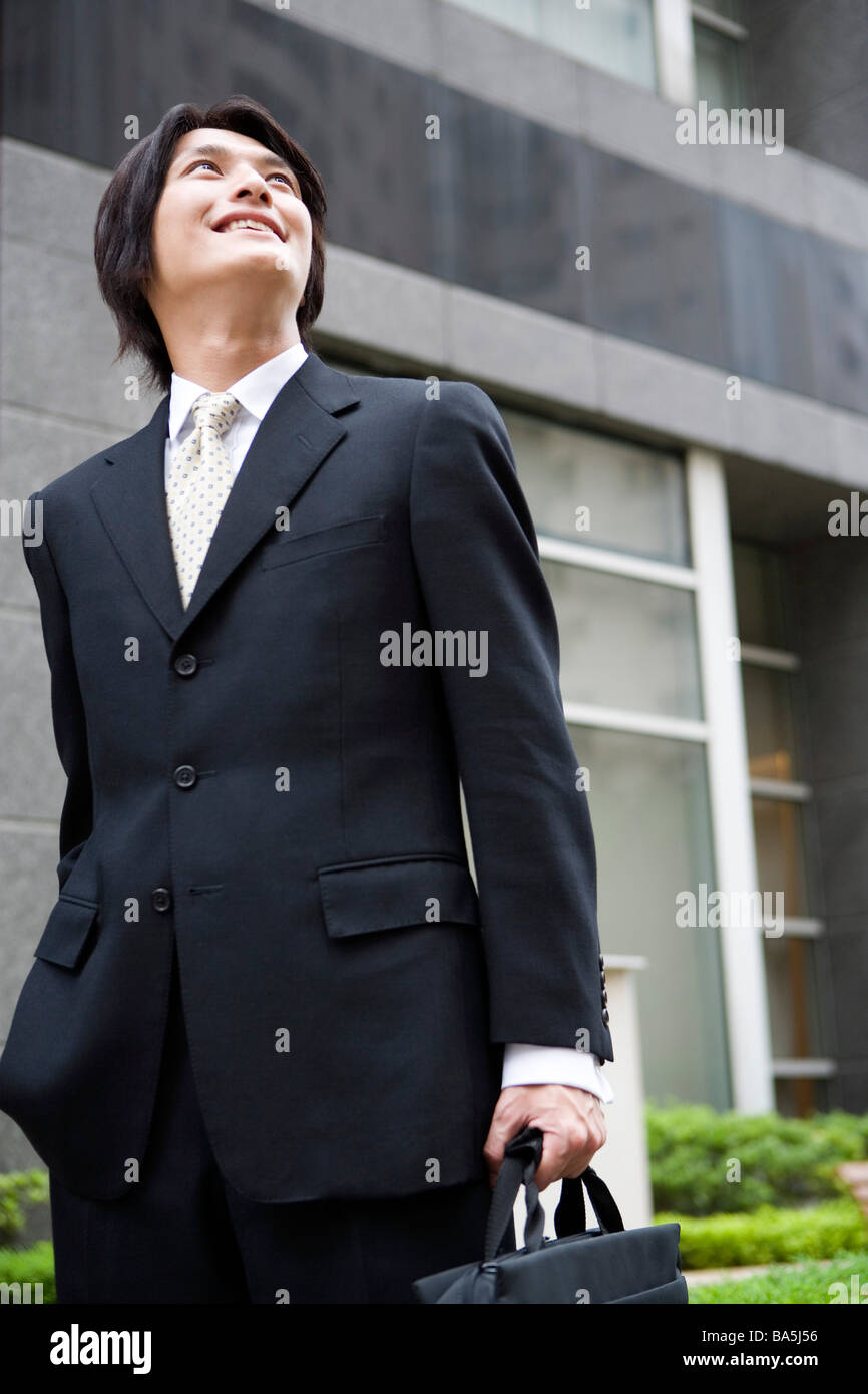 Porträt der Geschäftsmann mit Aktenkoffer in der hand lächelnd auf der Straße stehen Stockfoto