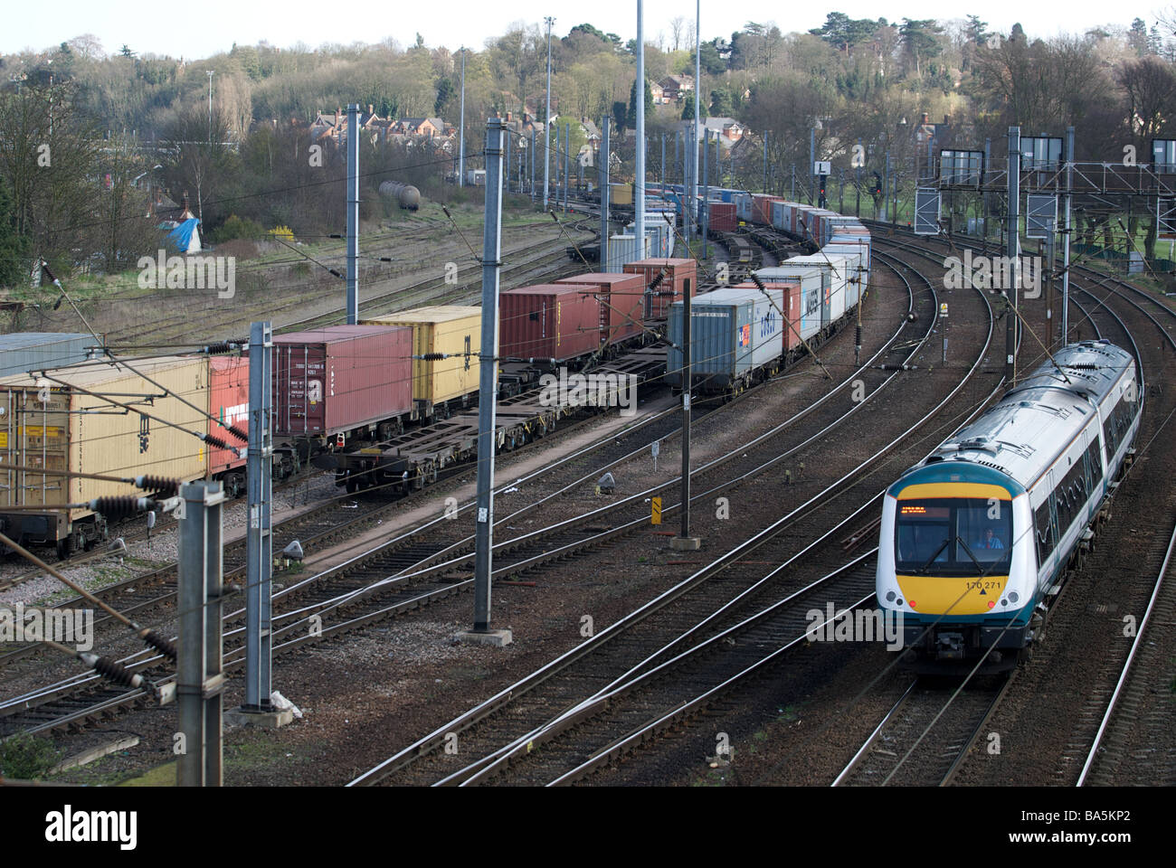 Personenverkehr Bahn vorbei an Fracht Container Wagen, Ipswich, Suffolk, UK. Stockfoto