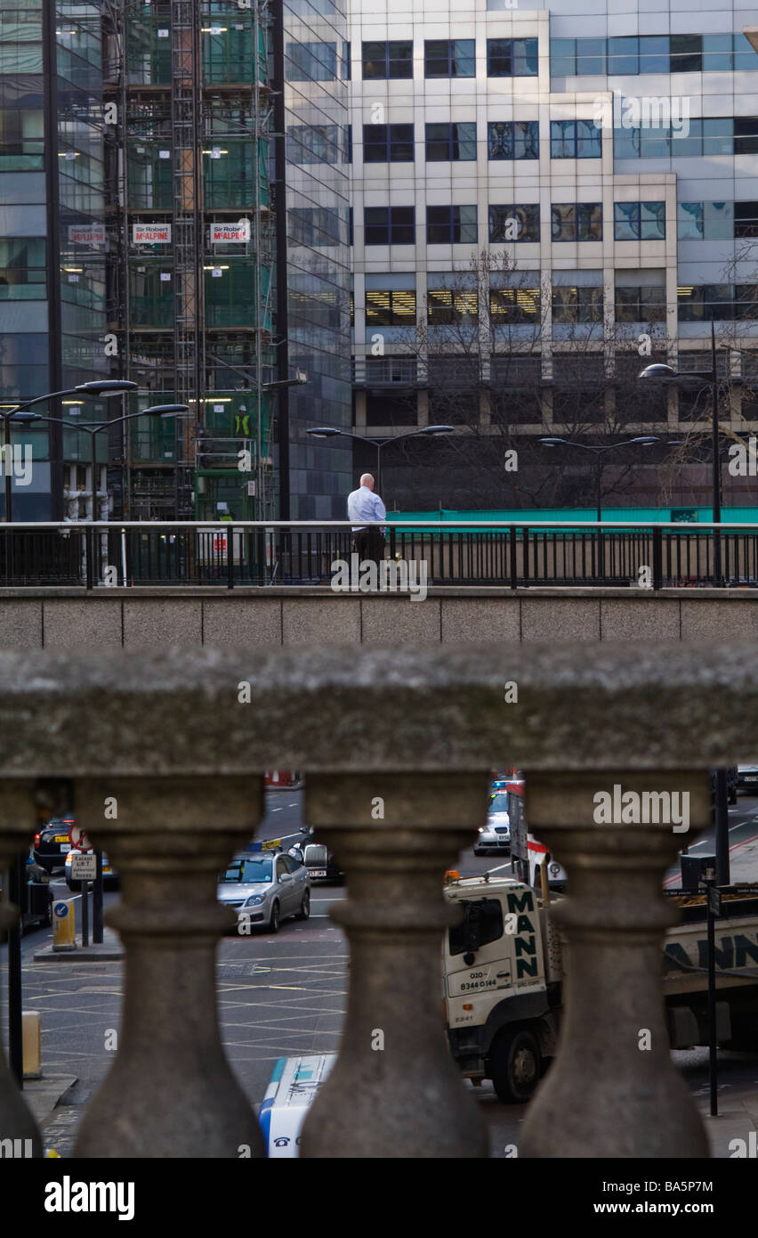 Ein Mann stand allein auf einer Brücke, umgeben von Bürogebäuden. Stockfoto