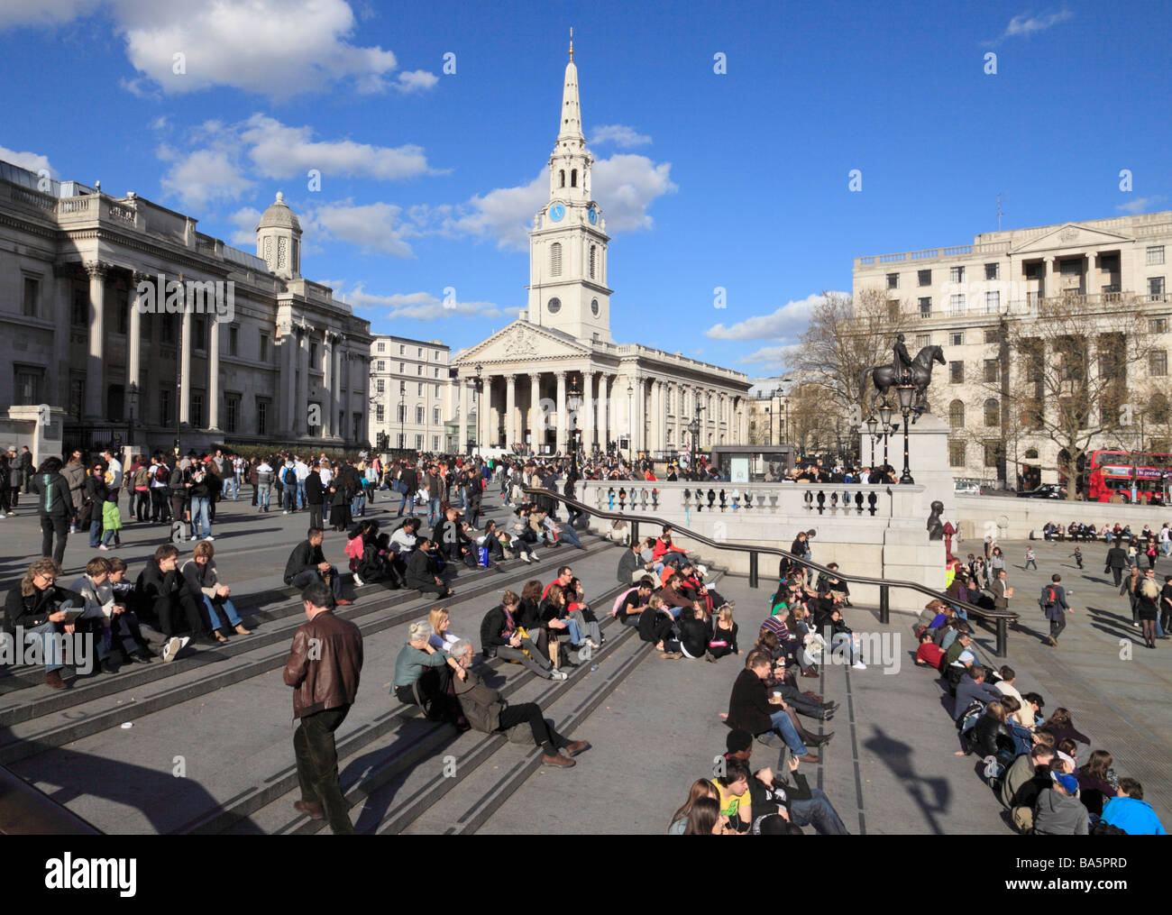 Leute sitzen herum und Trafalgar Square London England UK. Stockfoto