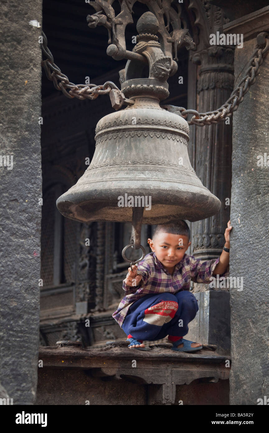 Kleiner Junge, der spielt, auf der Kante unter der Glocke. Kathmandu Nepal Asien. Vertikal 92721 Nepal-Kathmandu Stockfoto