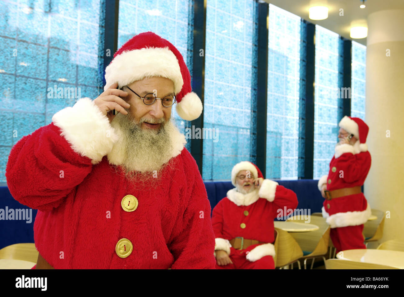 Cafeteria Santa Claus fröhlich Handys Telefone Unschärfe Weihnachten Menschen Männer drei Verkleidung Outfits Gläser Bärte Stockfoto