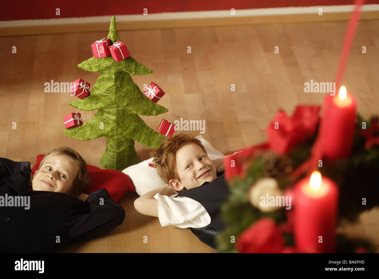 Gebiert zwei Lächeln Boden Lügen Weihnachtsdekoration Christian-Baum Geschenke Adventskranz Kerzen Burns Serie Menschen Kinder Stockfoto
