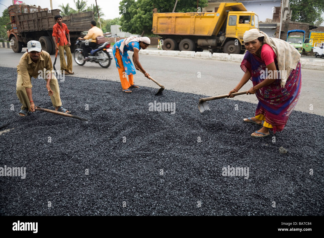 Männliche und weibliche Arbeiter / Straßenarbeiter Asphalt auf einer Straße in Surat zu verbreiten. Gujarat. Indien. Stockfoto