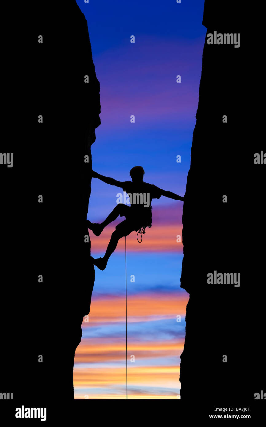 Kletterer, Silhouette, als er über einen Spalt erreicht. Stockfoto