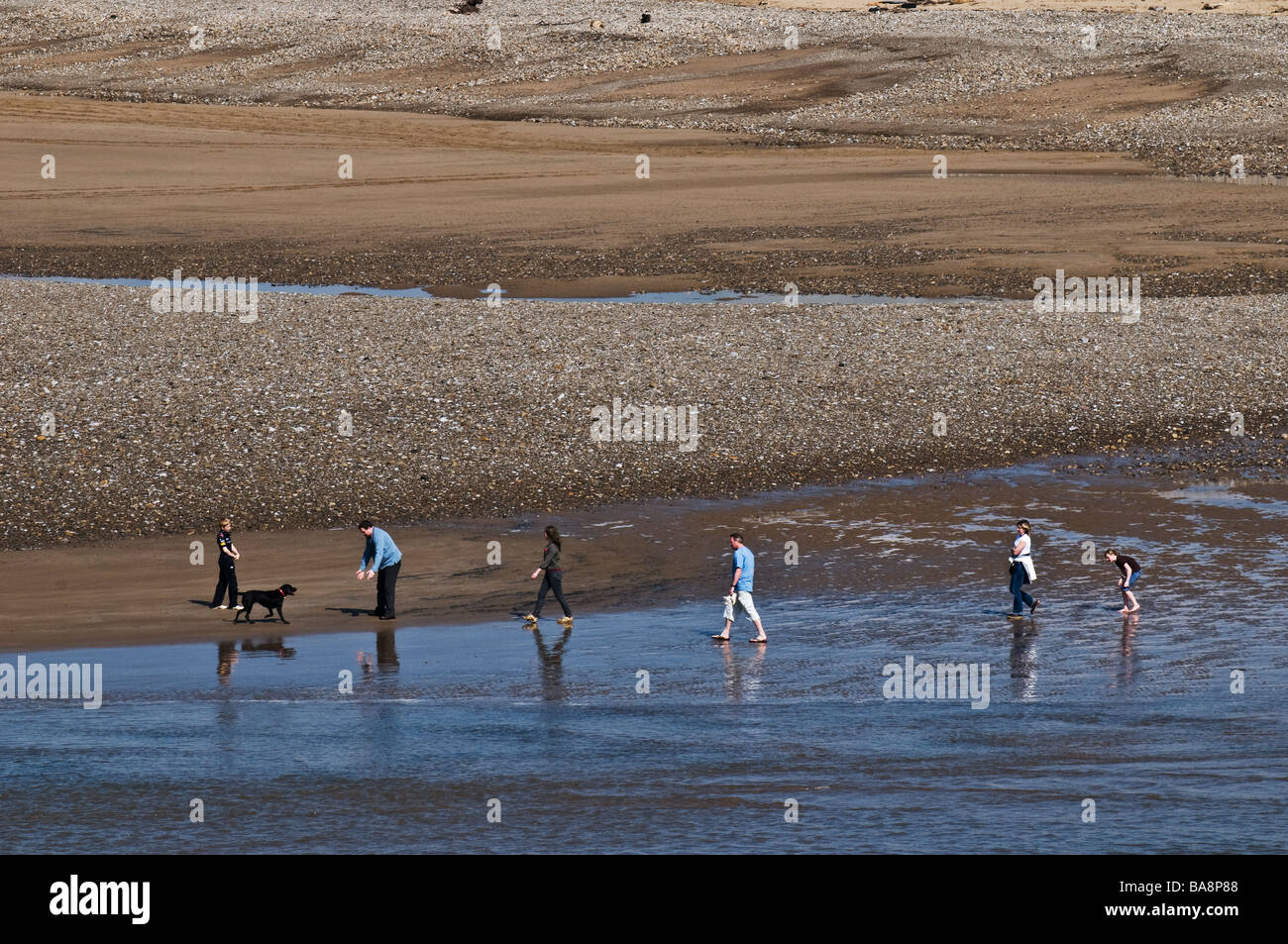 Eine Linie von Menschen zu Fuß am Strand entlang an Ogmore in Wales. Stockfoto