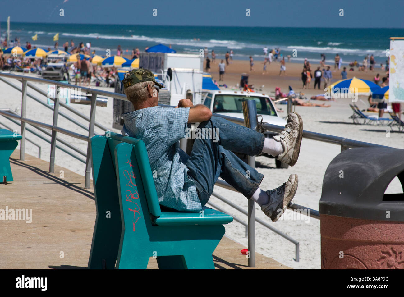 Transiente Obdachloser sitzt an einem Strand an einem touristischen Ort gefragt, woher seine nächste Mahlzeit kommen soll Stockfoto