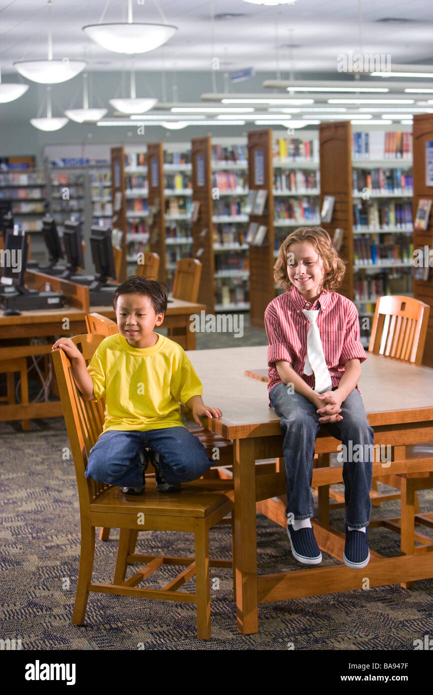 Asiatische und kaukasischen Grundschule Jungs sitzen in Bibliothek Stockfoto