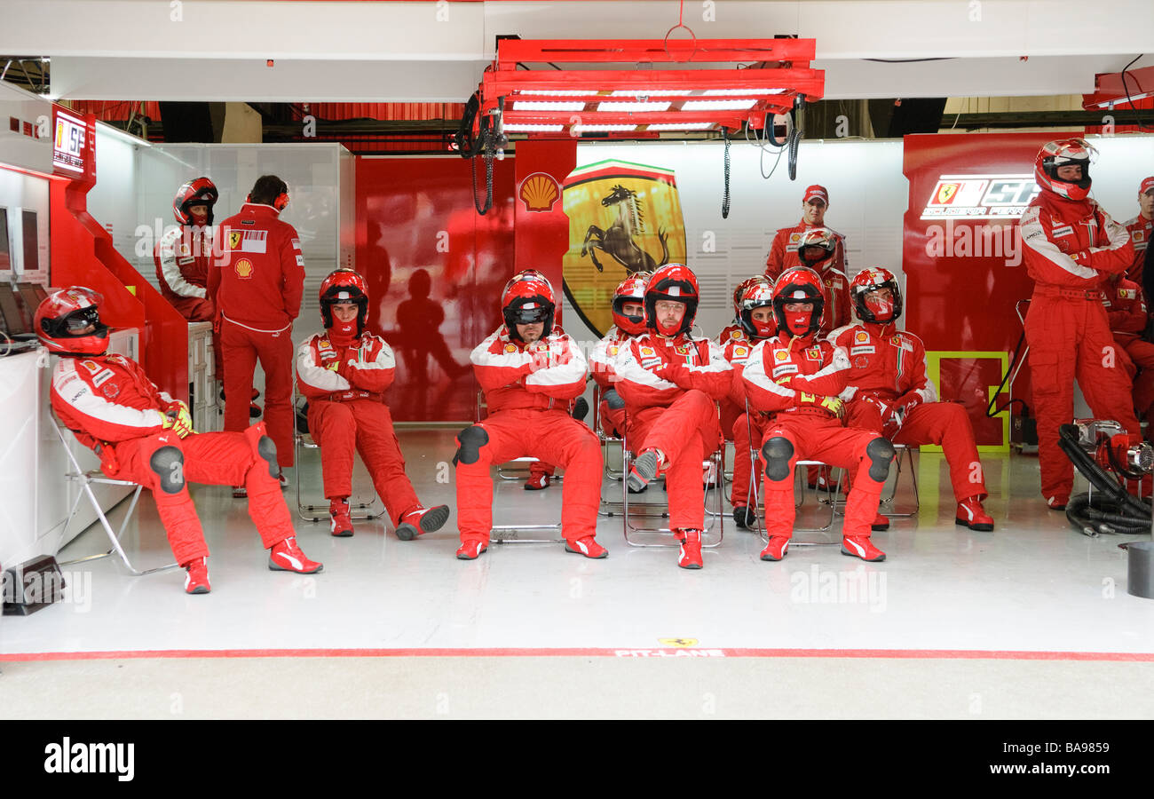 Ferrari Formel 1 Boxencrew sitzen in Garage und warten auf Boxenstopp Stockfoto