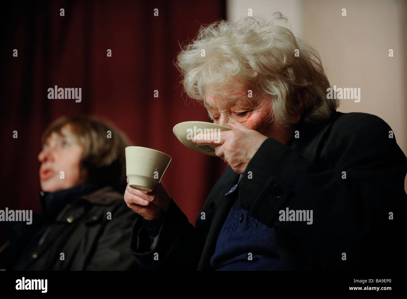 Eine Frau spaziert trinken Tee aus Untertasse. Bild von Jim Holden. Stockfoto