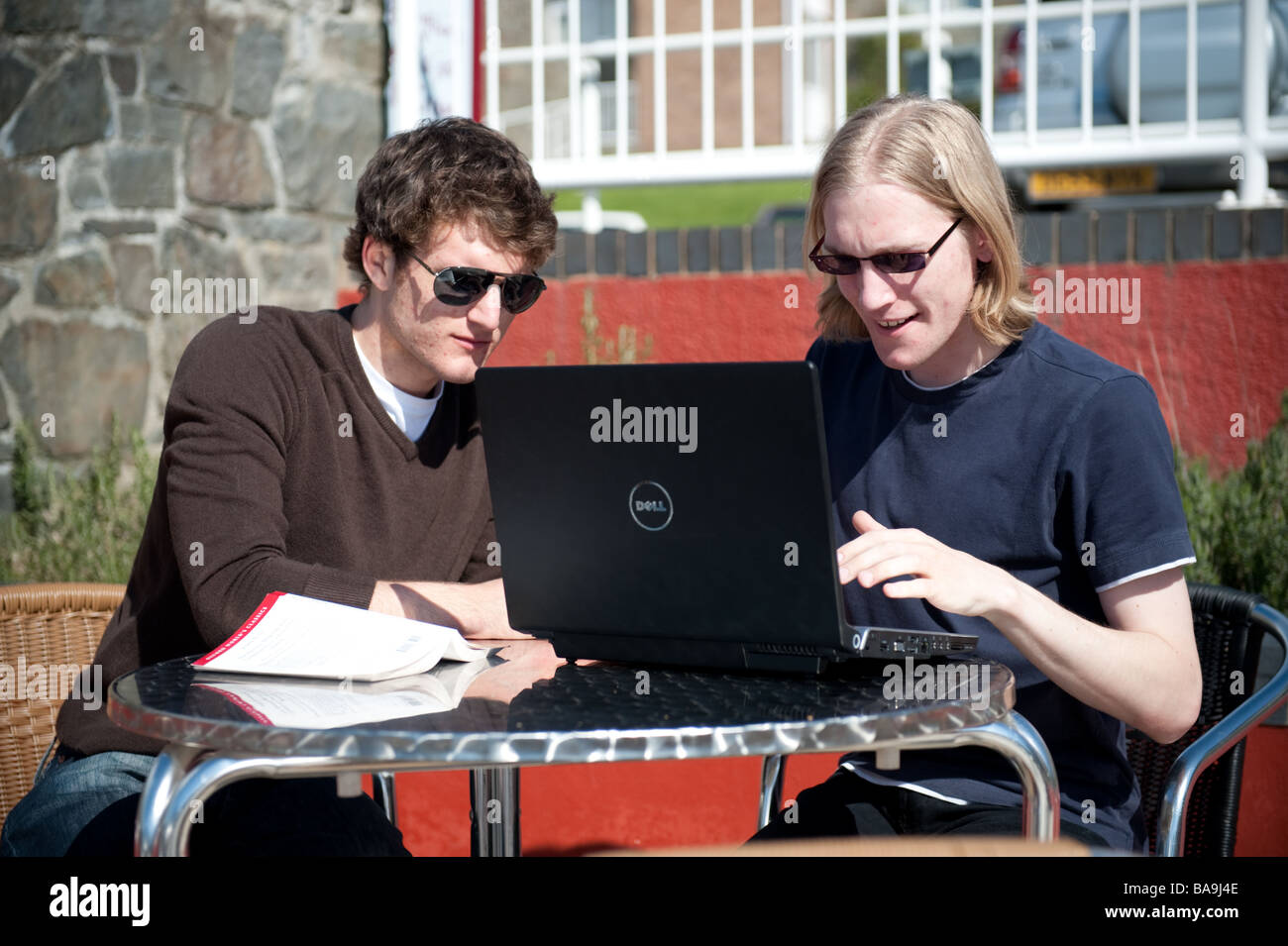 Zwei männliche Studenten an der Aberystwyth University mit einem Laptopcomputer im freien Zugriff auf dem Campus Drahtlosnetzwerk sonnigen Nachmittag Stockfoto