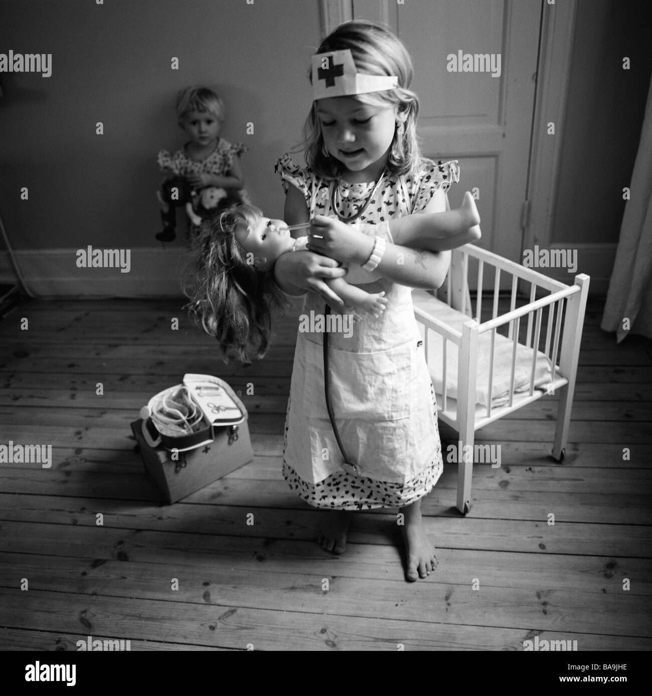 Mädchen spielen Arzt kümmert sich um eine Puppe, Schweden. Stockfoto