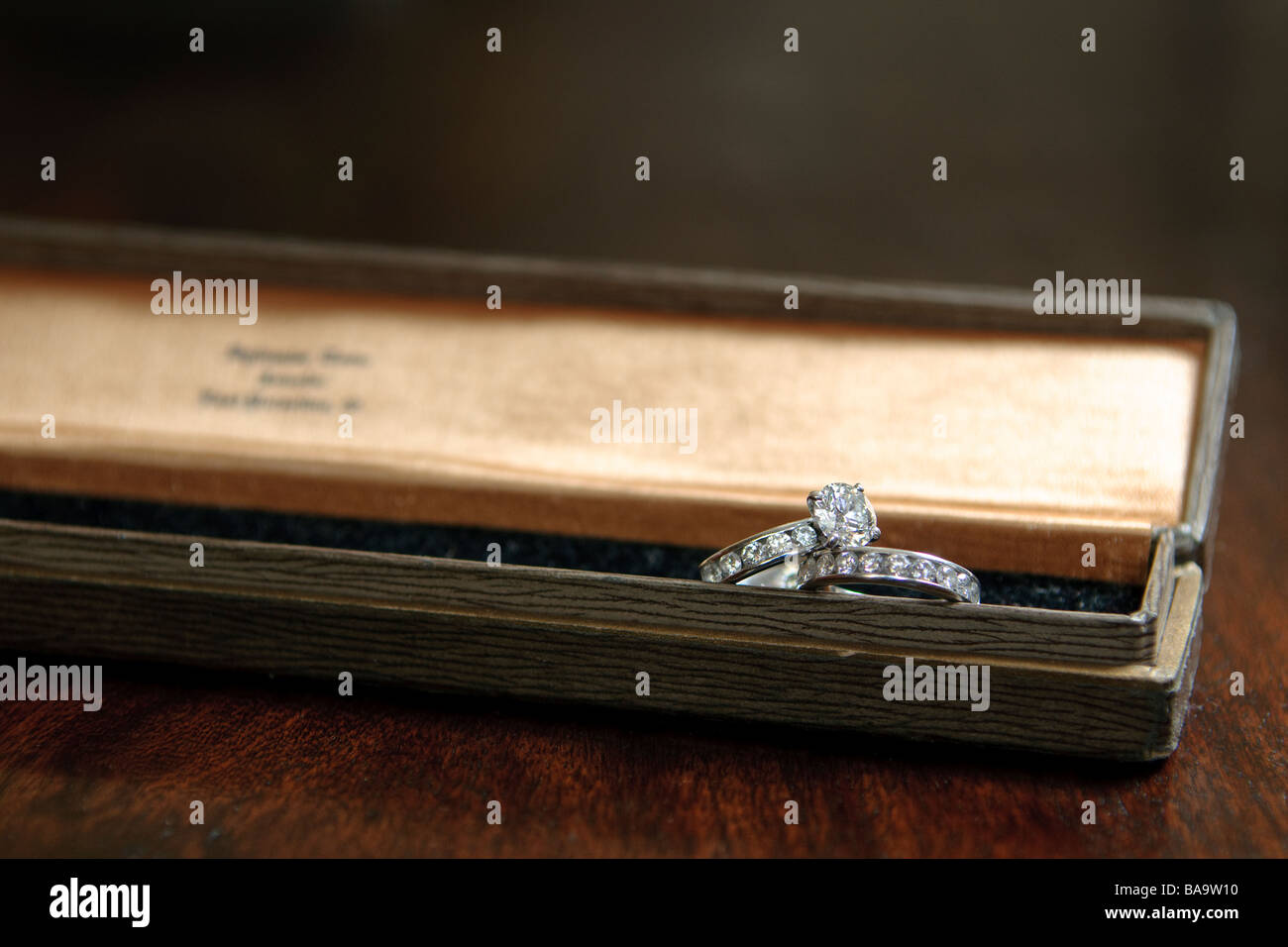 Ein Diamant und Platin Ehering Damen set ruht in einer langen Schmuck-Box auf einem Holztisch Stockfoto