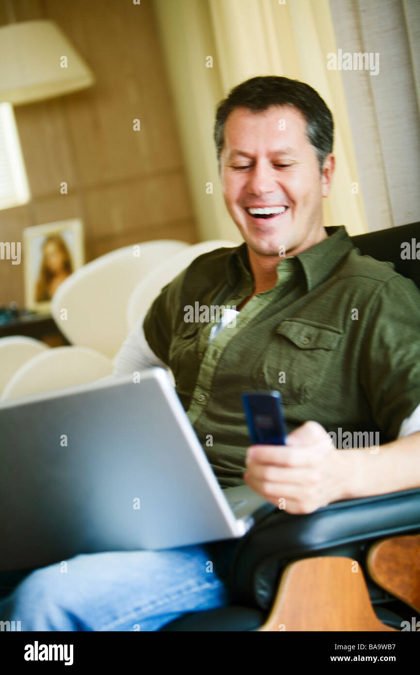 Skandinavische Mann mit einem Laptop mit seinem Mobiltelefon, Brasilien. Stockfoto