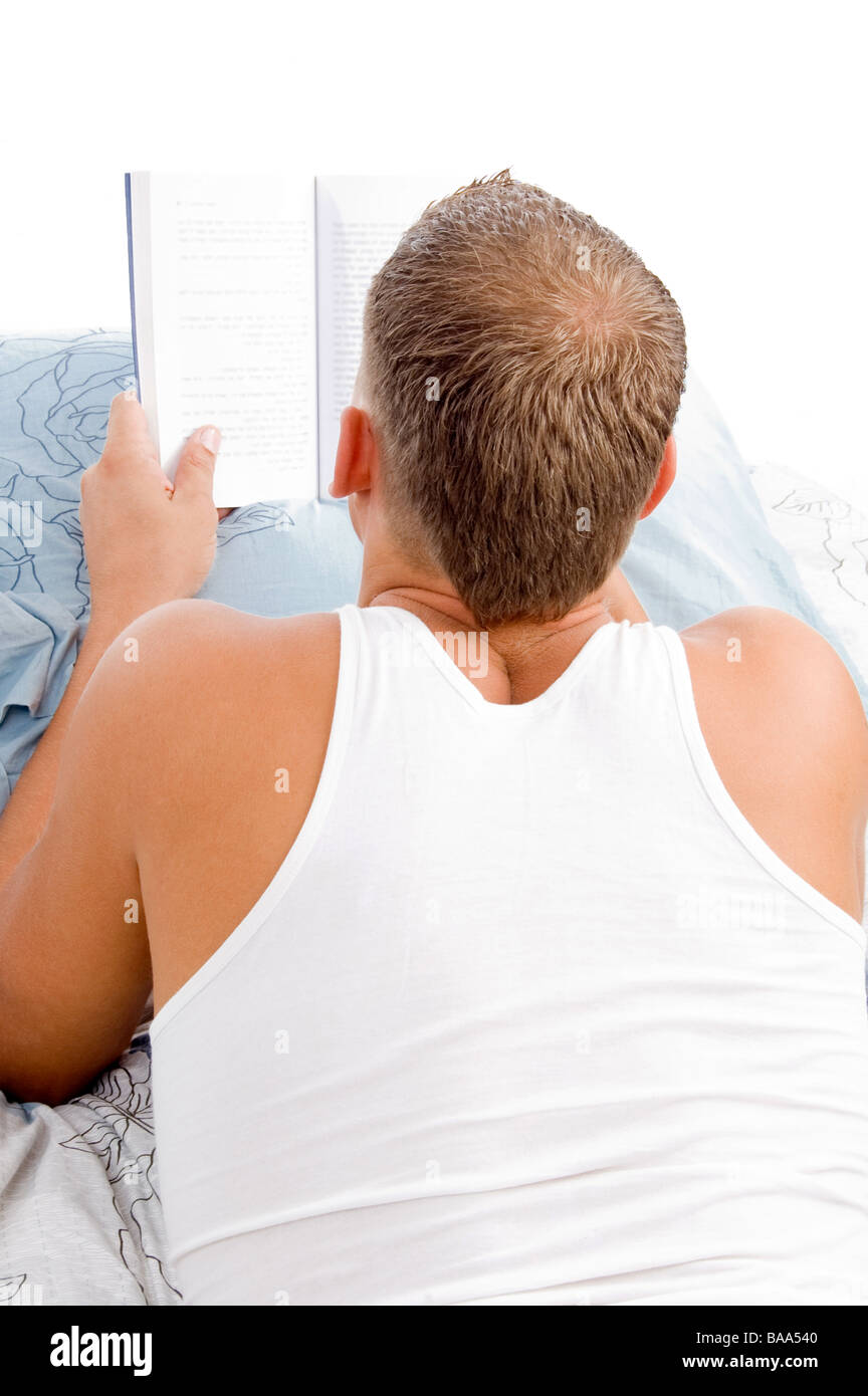 Mann liest Buch beim stillstehen auf Matratze Bett Stockfoto