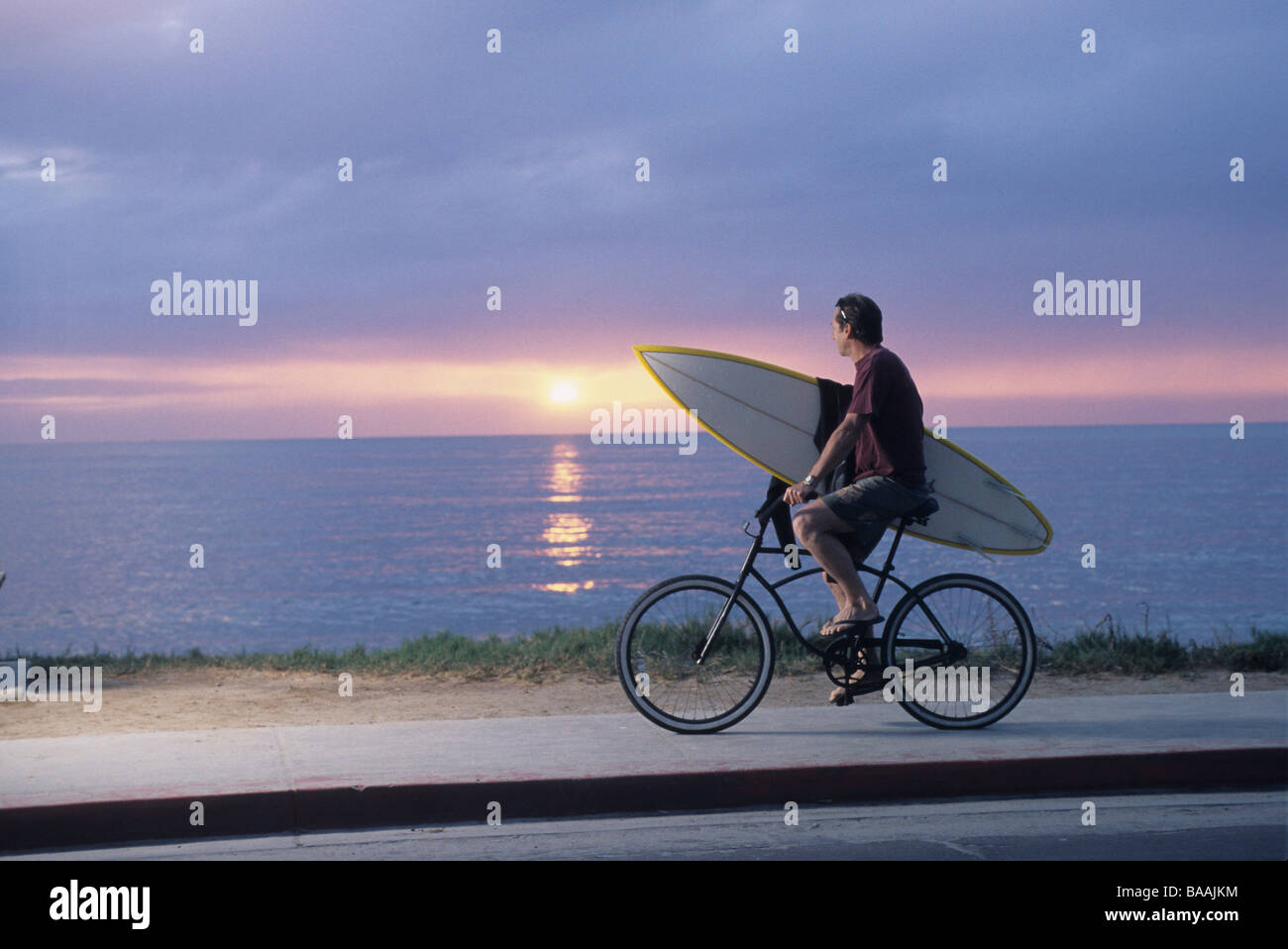 Mann Reiten Fahrrad mit Surfbrett in La Jolla, Kalifornien. Stockfoto