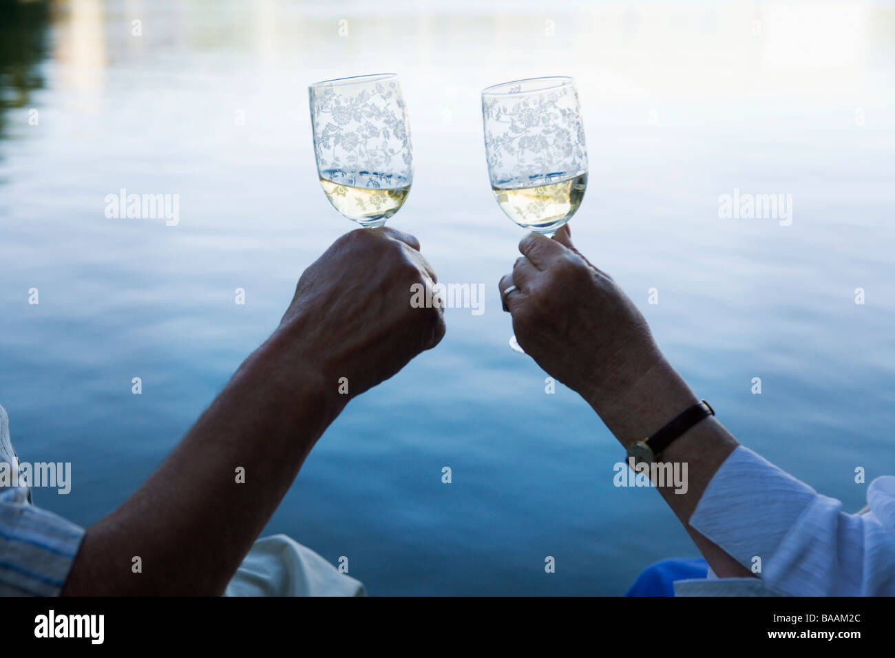 Die Hände der ein älteres paar Toasten auf einem Steg, Schweden. Stockfoto