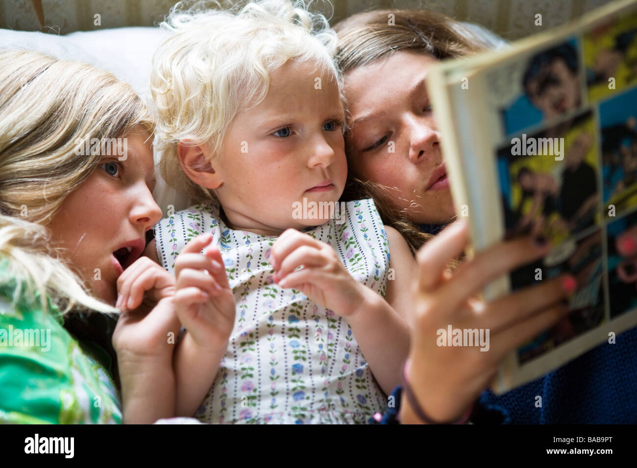 Drei Schwestern Lesen eines Comics Papier zusammen Schweden. Stockfoto