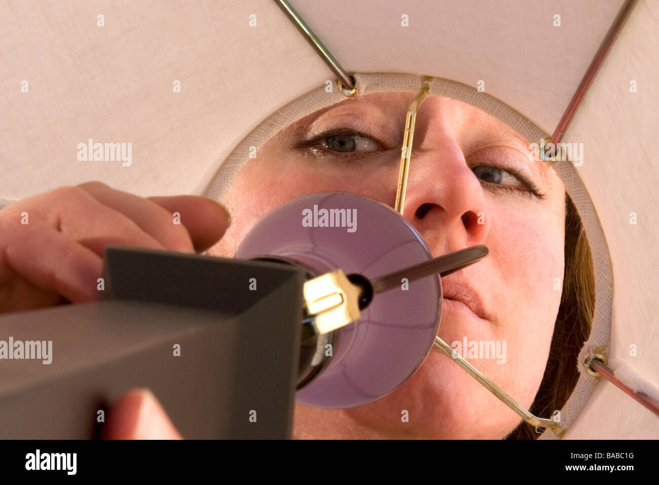 Eine Nahaufnahme von einer Frau in einer Lampe zu erreichen um ihn einzuschalten. Stockfoto