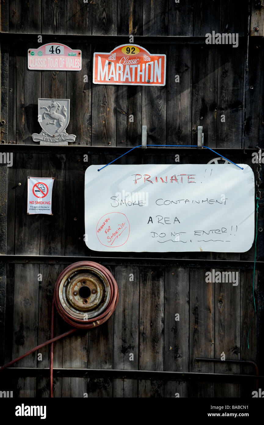 Eine rustikale Holz Garagentor mit alte Kfz Schilder und eine handgefertigte Private unterschreiben Warnung Besucher von Zigarettenrauch. Stockfoto