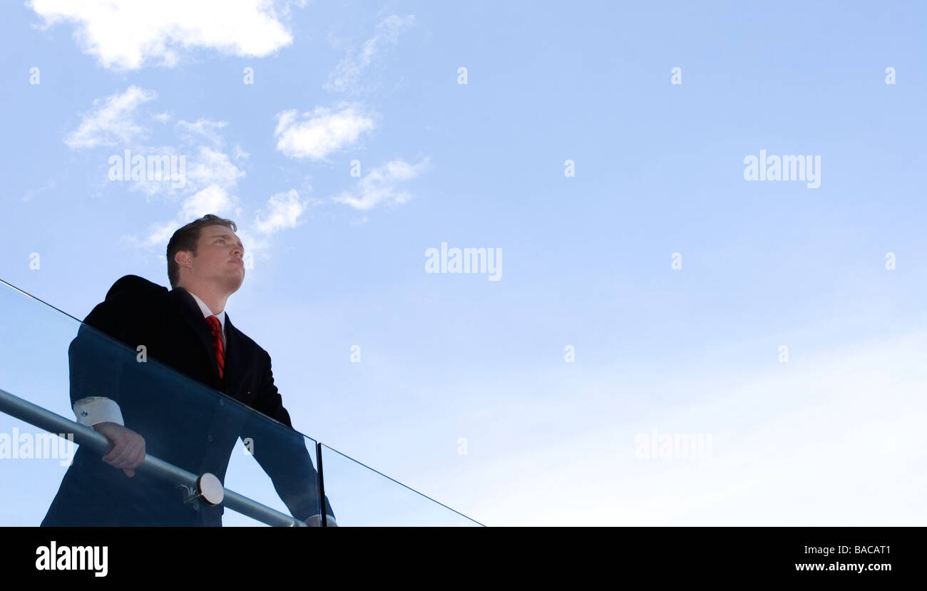 Business-Mann im schwarzen Anzug und roter Krawatte steht über Geländer Stockfoto