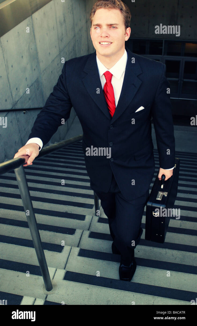 Business-Mann im schwarzen Anzug und rot binden lächelt, während er die Treppe hinauf geht Stockfoto