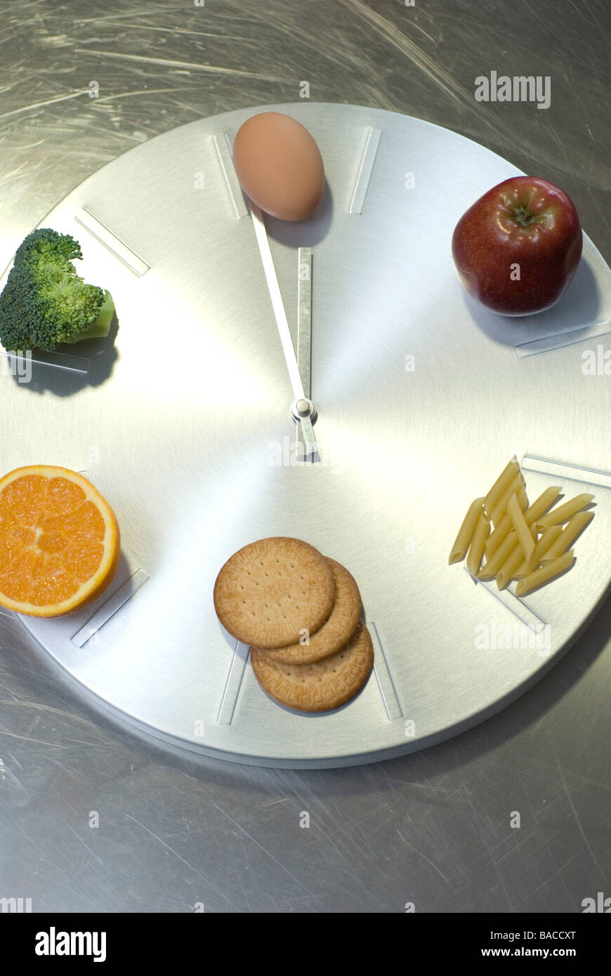 Uhr Essen Kontrolle-Nudeln, Kekse, Orange, Apfel, Ei und Brokkoli Stockfoto