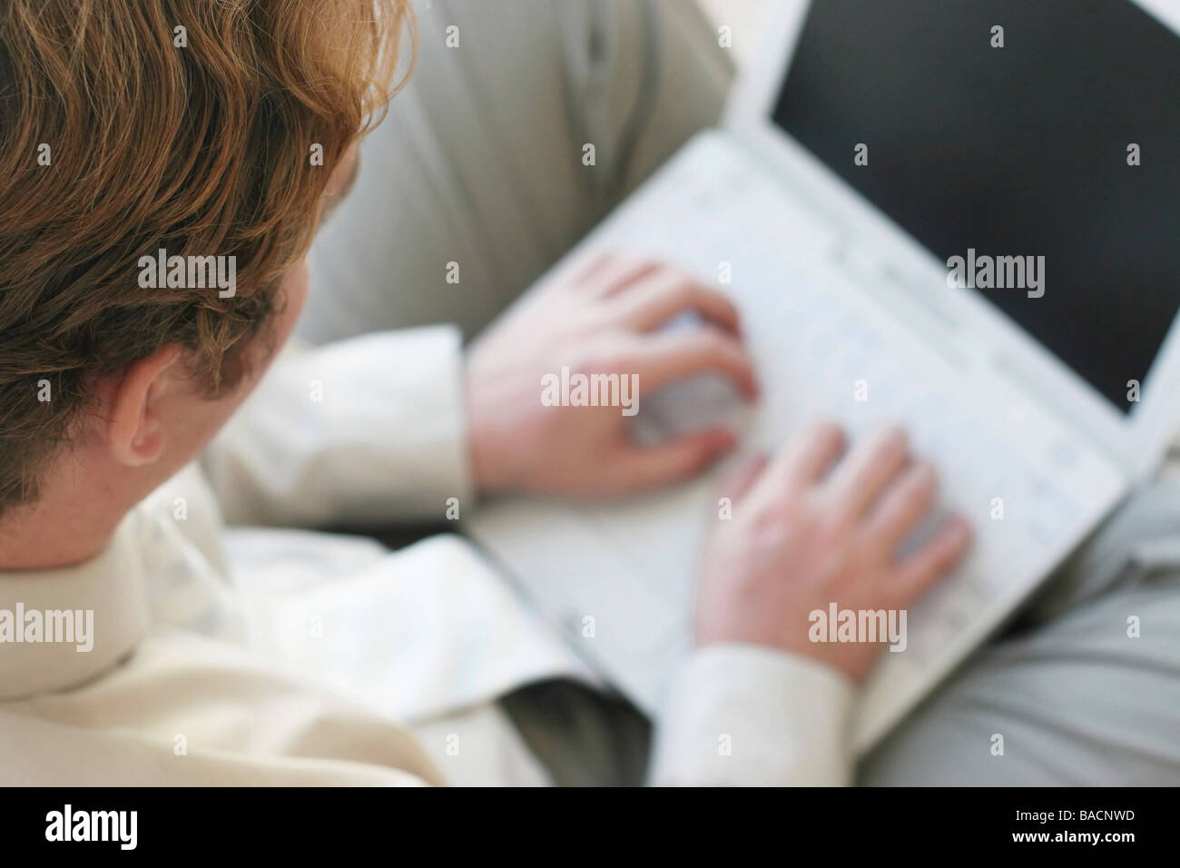 Geschäftsmann mit braunen Haaren und Tan Hemd ist auf seinem weißen Laptop tippen. Stockfoto