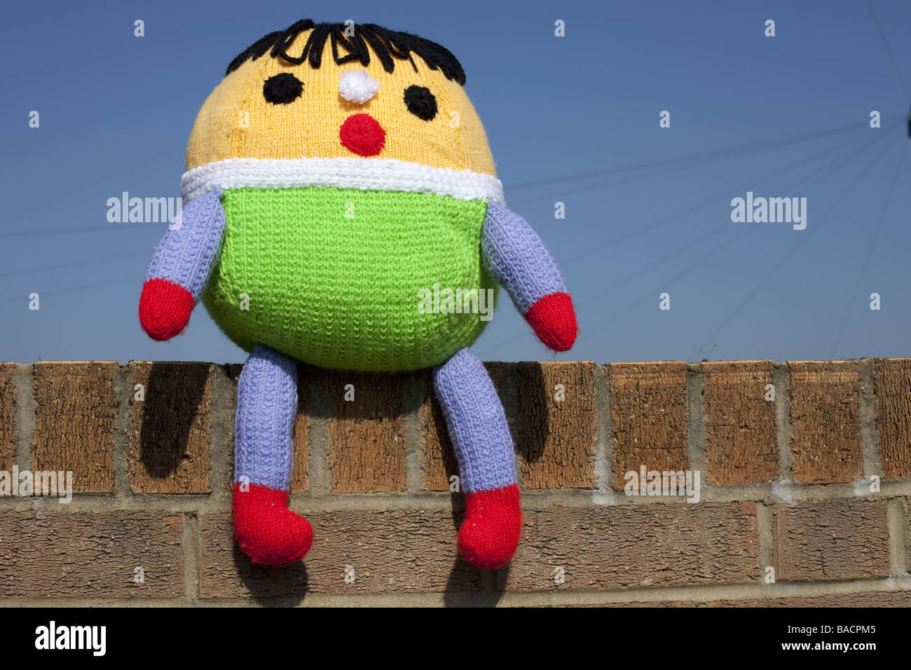 Ein Kuscheltier Humpty Dumpty saß auf der Wand mit einem blauen Himmelshintergrund. Stockfoto