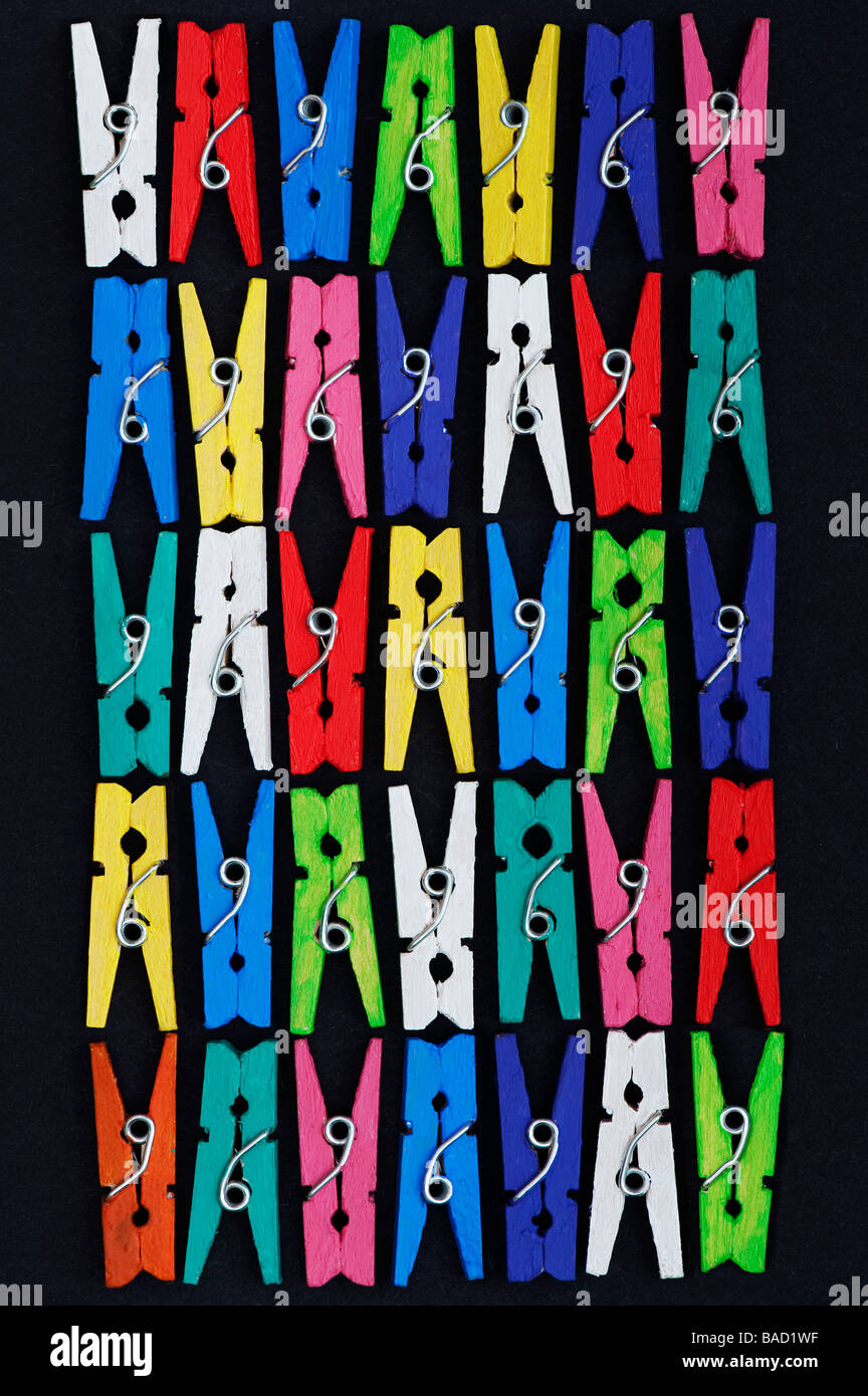 Farbige kleine Wäscheklammern Muster auf schwarzem Hintergrund Stockfoto