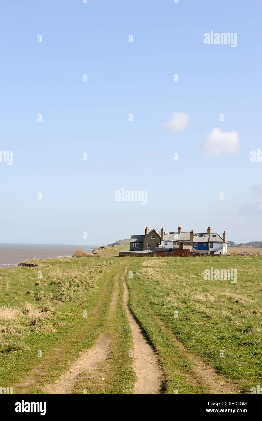 Küstenerosion nahe Waxham, North Norfolk, England, UK. Verlassene Häuser auf der Klippe mit Gärten fallen ins Meer. Stockfoto