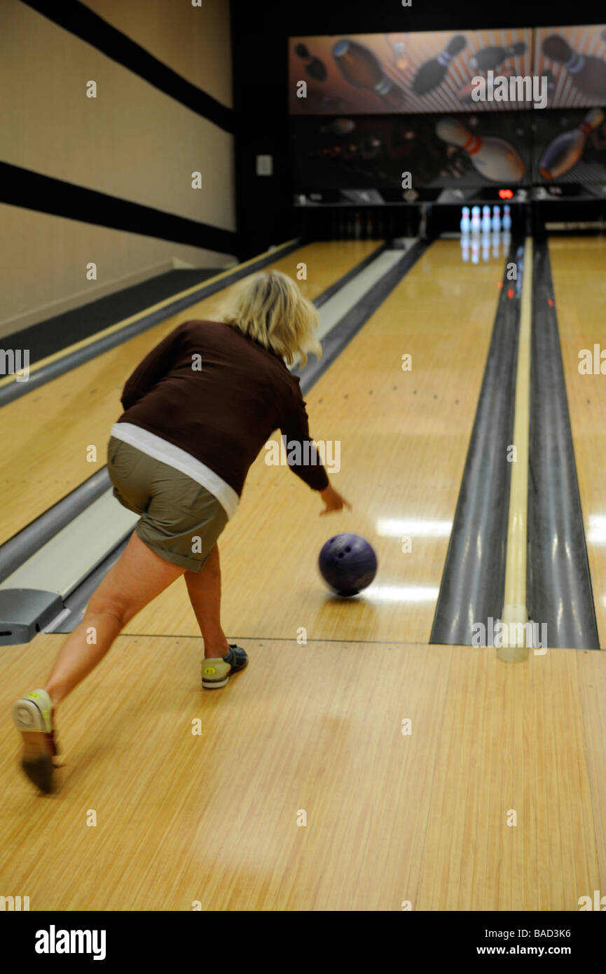 Weiße weibliche Bowling und wirft Ball unten Lane Aiiming an pins Stockfoto