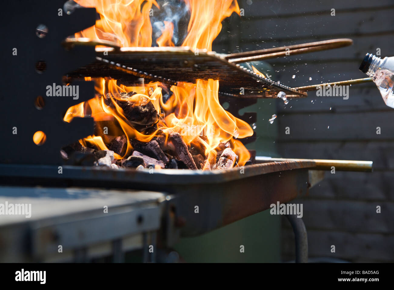 Spritzen Beleuchtung flüssigen Brennstoff auf einem Holzkohlegrill Bar-B-Q um die Flammen zu erhöhen. Stockfoto