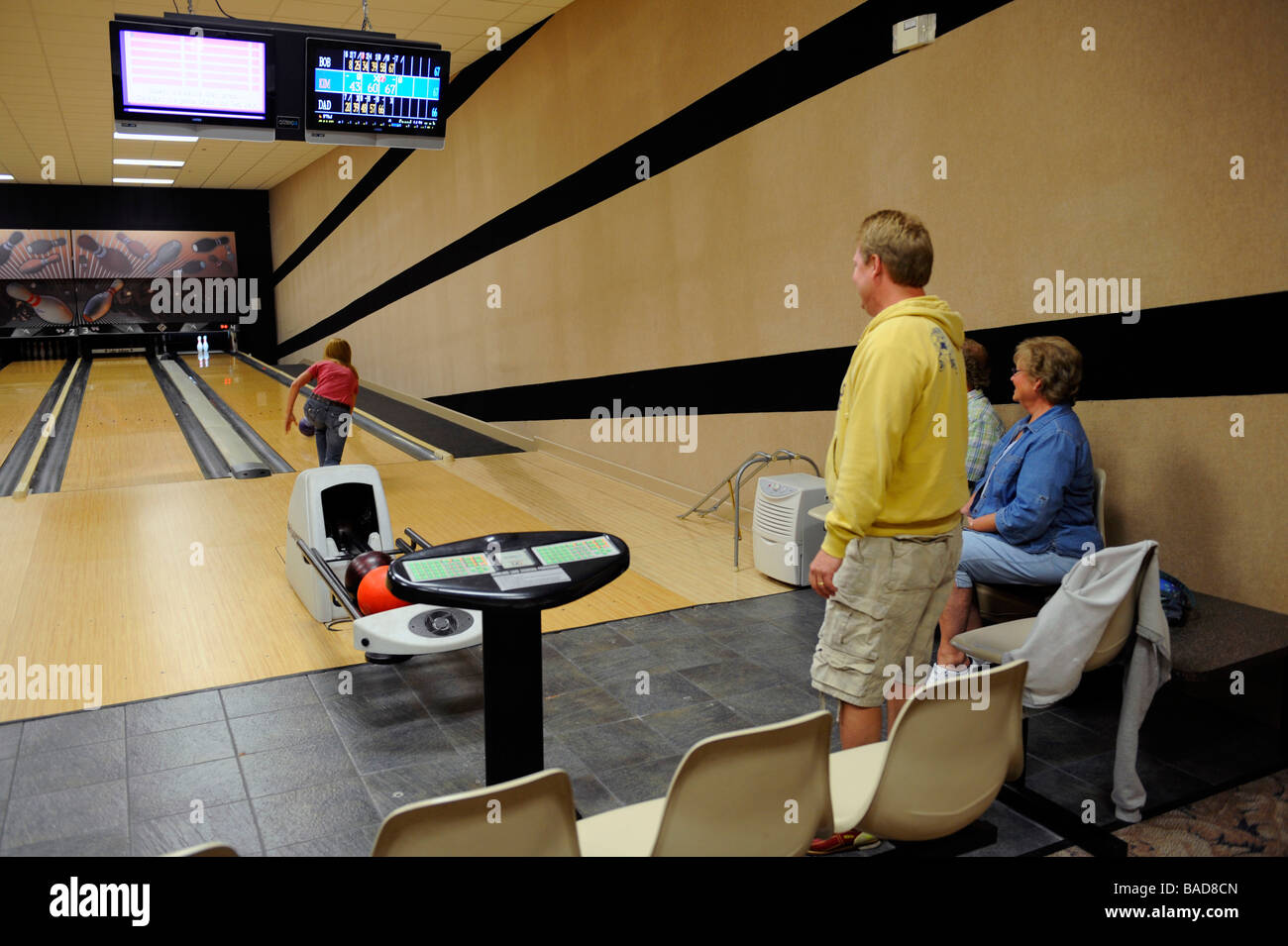 Team-Mitglieder sehen Teammitglied Bowling-Kugel Gasse in bowling Allley werfen Stockfoto