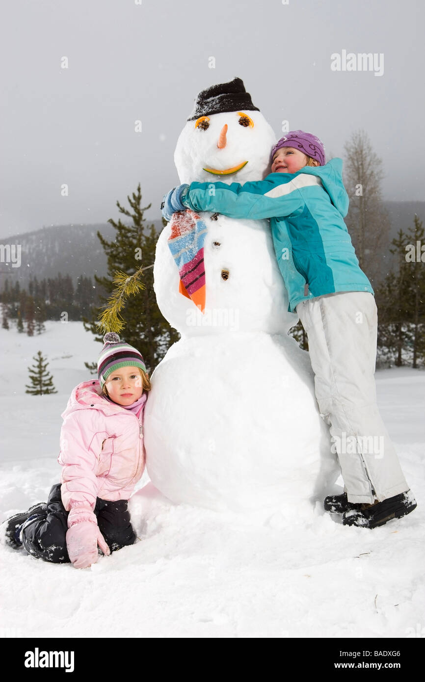 Mädchen umarmt Schneemann, in der Nähe von Frisco, Summit County, Colorado, USA Stockfoto