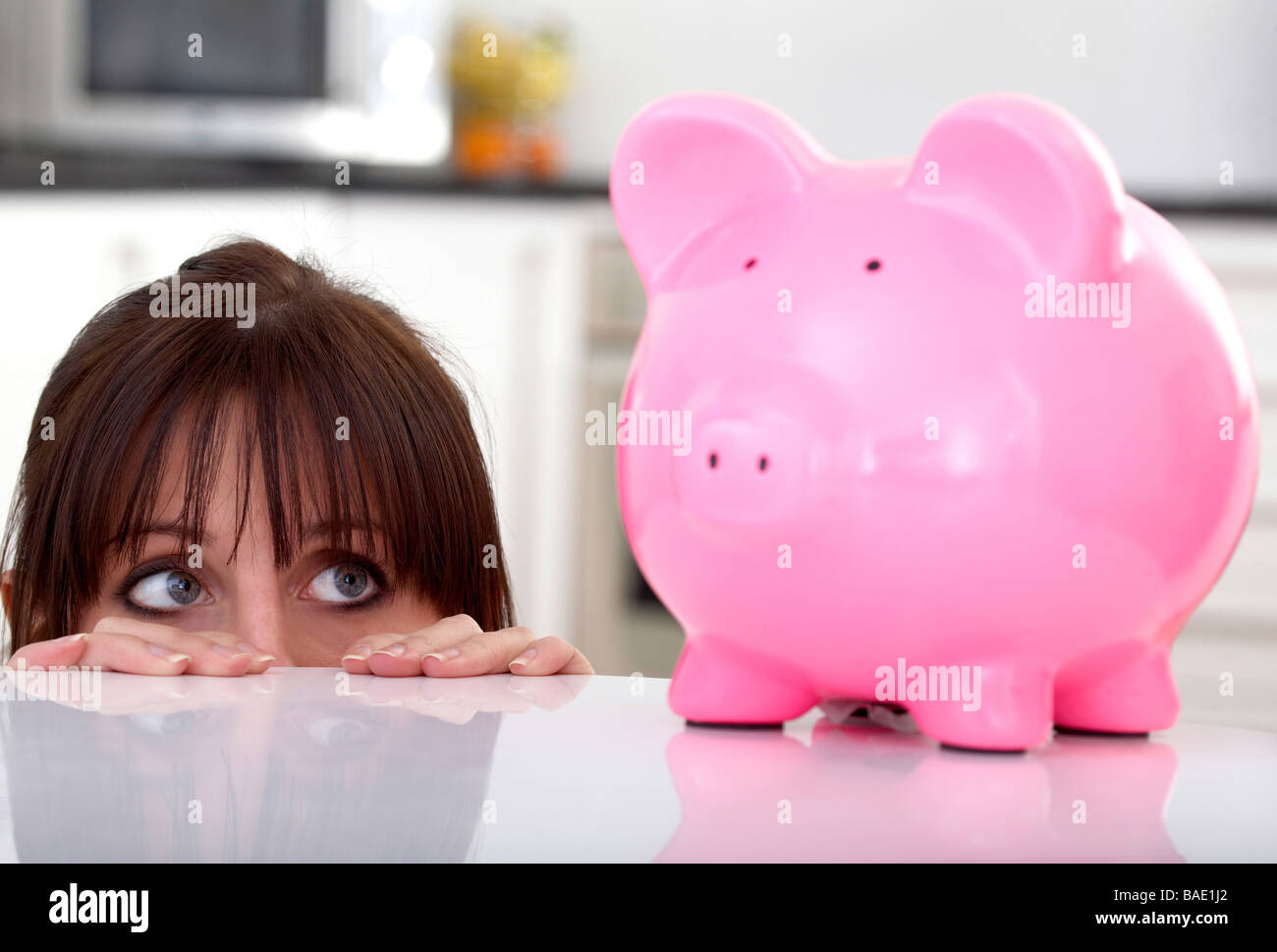 Mädchen auf der Suche Angst von ihren Ersparnissen in ein rosa Sparschwein Stockfoto